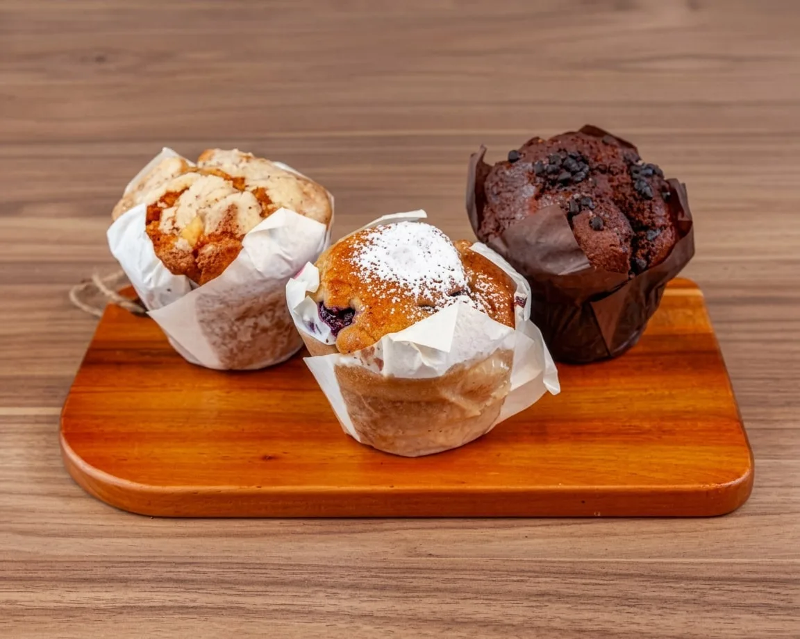 Blueberry, chocolate and almond muffins on a wooden board