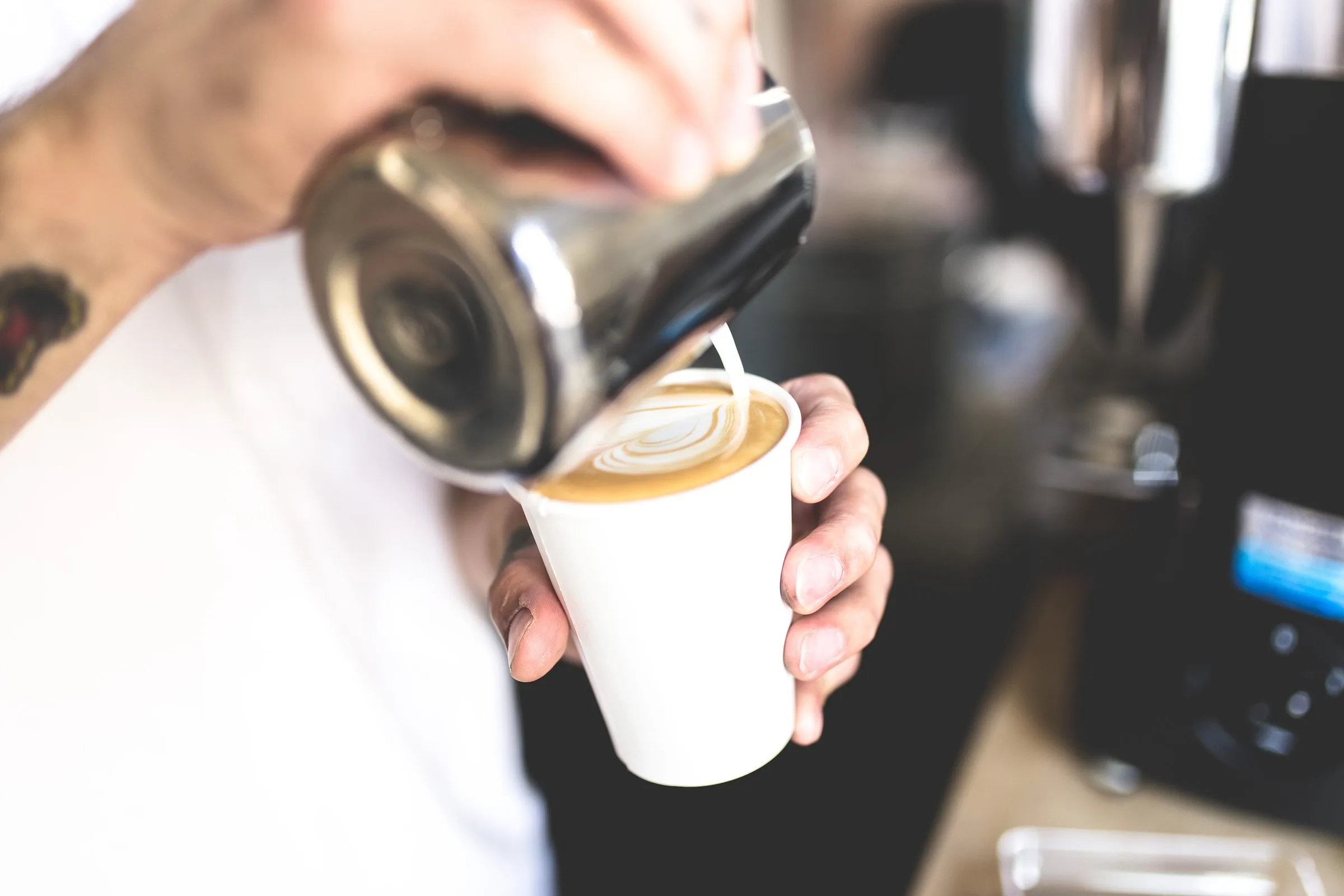 A barista pouring steamed milk into a coffee